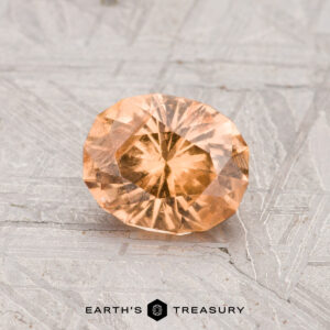 A 1.09-carat oval-cut Grossular Garnet gemstone is showcased on a gray, patterned surface with "Earth's Treasury" displayed at the bottom.