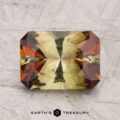 A 2.52-carat Andalusite with rectangular facets and yellow-green and reddish-brown color zones, displayed on a textured gray surface with "Earth's Treasury" below.
