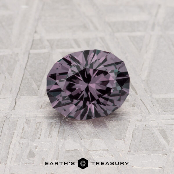 0.97-Carat Color Change Garnet A 0.97-carat color change garnet, round and faceted with a rich purple hue, is shown on a textured surface with "Earth's Treasury" displayed below the gemstone.