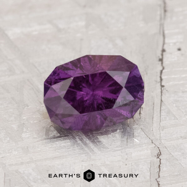 1.42-Carat Color Change Garnet 1.42-Carat Color Change Garnet, faceted oval gem shown on a textured light surface with "Earth's Treasury" at the bottom of the image.