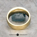A custom ring in 18k royal yellow gold with a 0.42-carat Montana sapphire stands upright on a textured gray surface, showcasing Earth's Treasury's classic Shasta-inspired design.