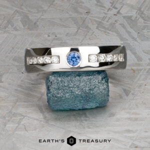 A ring from "Stacked from 53 images. Method=B (R=9,S=4)" with a central blue gemstone and side stones is balanced on a rough blue crystal, shown above the text "Earth's Treasury.