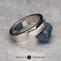 The "Stacked from 54 images. Method=B (R=9,S=4)" ring, featuring five diamonds and a central blue gemstone, is showcased resting on a rough blue mineral atop a textured gray surface.