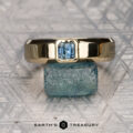 The product "Stacked from 16 images. Method=B (R=10,S=7)" is showcased as a classic gold Sapphire Ring with a square-cut blue gemstone, standing on a rough blue stone atop a patterned silver surface marked "EARTH'S TREASURY.