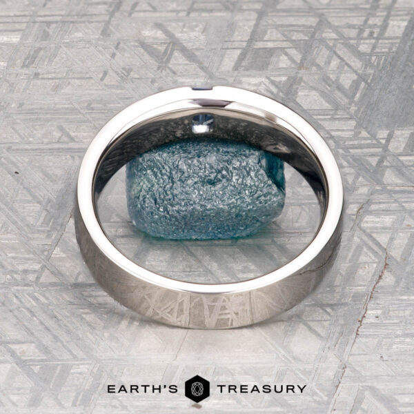 The "Elgon" ring in platinum with light blue sapphire Harrison, Samuel 3," a classic ring with a textured blue stone, is displayed on a patterned surface with "Earth's Treasury" at the bottom.