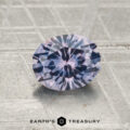 A round, faceted 1.37-carat heated Montana Sapphire sits on a textured gray surface with the "EARTH'S TREASURY" logo beneath it.