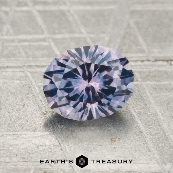1.37-Carat Montana Sapphire (Heated) A round, faceted 1.37-carat heated Montana Sapphire sits on a textured gray surface with the "EARTH'S TREASURY" logo beneath it.