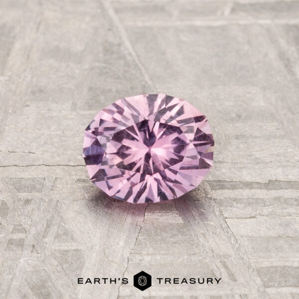 0.68-Carat Montana Sapphire A 0.68-carat Montana Sapphire, round brilliant-cut, is displayed on a textured gray surface with the text "Earth's Treasury" at the bottom.