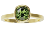 The ring-bezel is a gold ring featuring a bezel-set, round green gemstone.