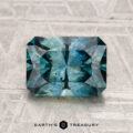 A rectangular step-cut 2.70-carat heated Montana sapphire in blue-green is displayed on a light textured surface, with "EARTH'S TREASURY" at the bottom.