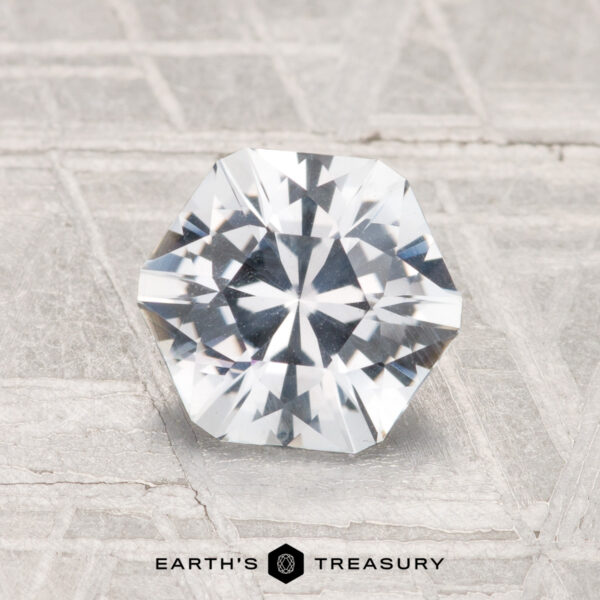 1.49-Carat Montana Sapphire A faceted, octagonal 1.49-carat Montana Sapphire rests on a textured light gray surface with the "Earth's Treasury" logo and text at the bottom.