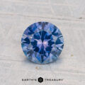 A 1.32-carat heated Montana sapphire gemstone is displayed on a textured light surface with "EARTH'S TREASURY" text at the bottom.