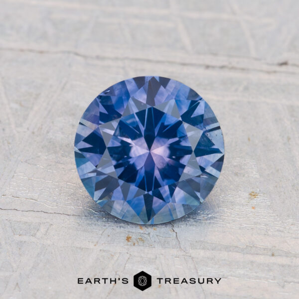 1.32-Carat Montana Sapphire (Heated) A 1.32-carat heated Montana sapphire gemstone is displayed on a textured light surface with "EARTH'S TREASURY" text at the bottom.
