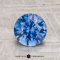 A 2.00-carat round brilliant-cut heated Montana Sapphire is displayed on a light textured surface with "EARTH'S TREASURY" below.