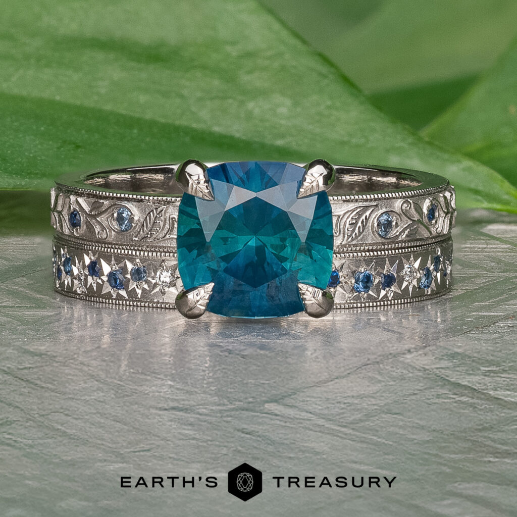 The "Stacked from 37 images. Method=B (R=11,S=7)" ring features a silver engraved band with a large blue center gemstone and small blue side stones, showcased on a textured surface.