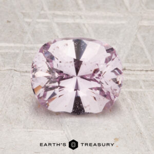 A 1.81-carat Ceylon sapphire is displayed on a textured light gray surface, with "EARTH'S TREASURY" text below.