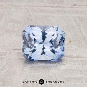 A 1.18-carat Ceylon Sapphire (Heated) is displayed on a textured gray surface with the words "Earth's Treasury" beneath it.