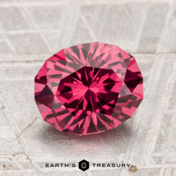 2.51-Carat Tanga Garnet A 2.51-carat Tanga Garnet, faceted in an oval cut, is displayed on a textured, light surface with "Earth's Treasury" beneath it.
