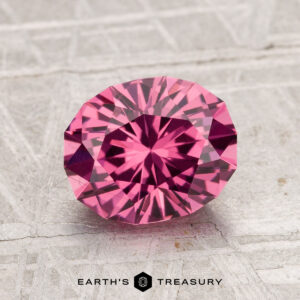1.97-carat Tanga Garnet in round brilliant cut showcased on a textured light surface, featuring "EARTH'S TREASURY" at the bottom.