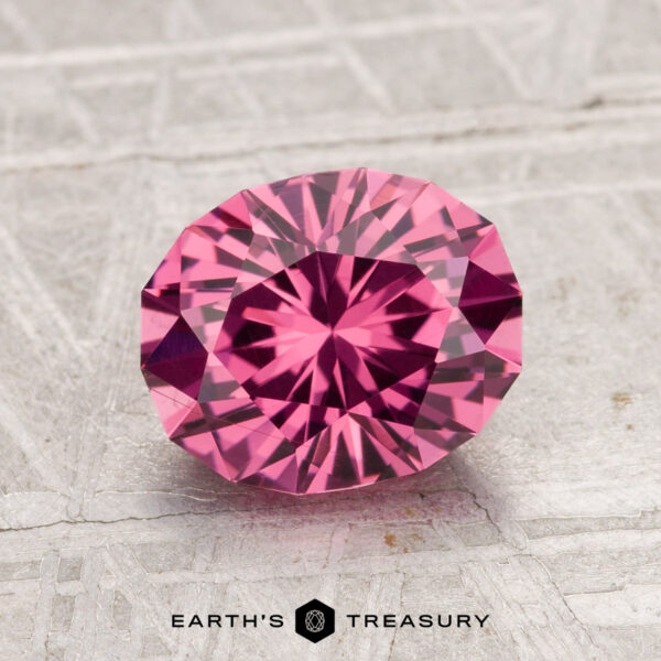 1.97-Carat Tanga Garnet 1.97-carat Tanga Garnet in round brilliant cut showcased on a textured light surface, featuring "EARTH'S TREASURY" at the bottom.