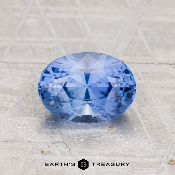 1.78-Carat Ceylon Sapphire A faceted oval 1.78-carat Ceylon Sapphire rests on a textured surface, with the "Earth's Treasury" logo visible at the bottom of the image.