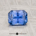 A 1.41-carat, rectangular cornflower blue Ceylon Sapphire rests on a light textured surface with "EARTH'S TREASURY" below.