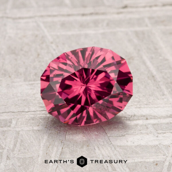 1.49-Carat Tanga Garnet The 1.49-Carat Tanga Garnet, a round faceted pink gemstone, is displayed on a light textured surface with "Earth's Treasury" at the bottom.