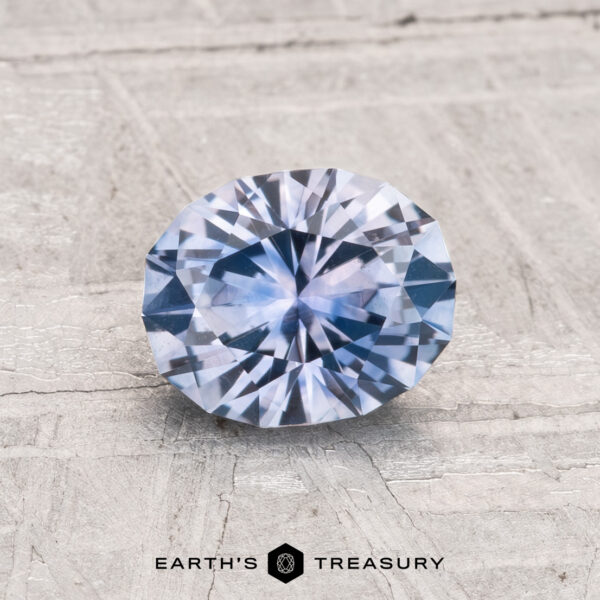 1.27-Carat Montana Sapphire (Heated) A 1.27-carat heated Montana sapphire, faceted in an oval cut, is displayed on a textured, light surface with "EARTH'S TREASURY" below.