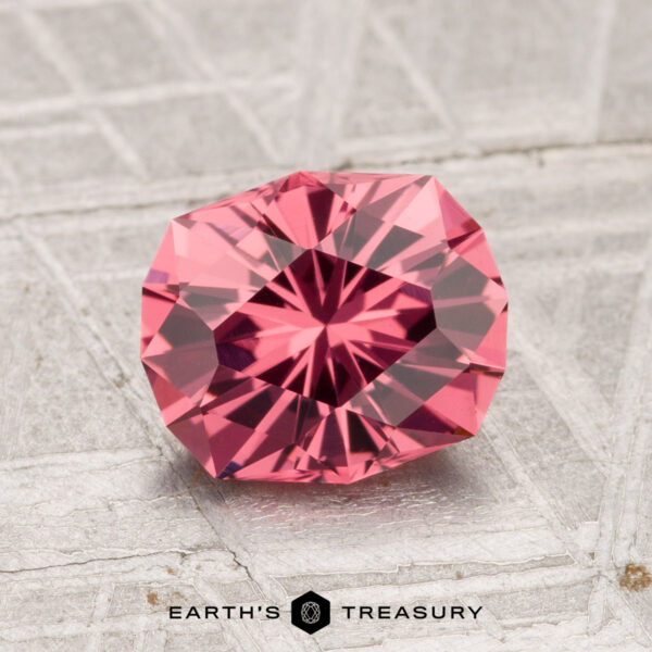 1.66-Carat Tanga Garnet A 1.66-carat Tanga Garnet, faceted in a geometric cut, is displayed on a textured gray surface. The Earth's Treasury logo is visible at the bottom.
