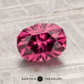 A 1.91-carat Tanga Garnet, cut in a faceted oval shape, is displayed on a textured gray surface with the Earth’s Treasury logo beneath it.