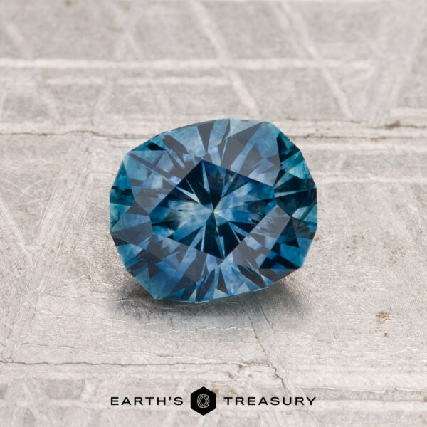 1.14-Carat Montana Sapphire (Heated) A 1.14-carat heated Montana sapphire is displayed on a textured grey surface, with the text "EARTH'S TREASURY" at the bottom.