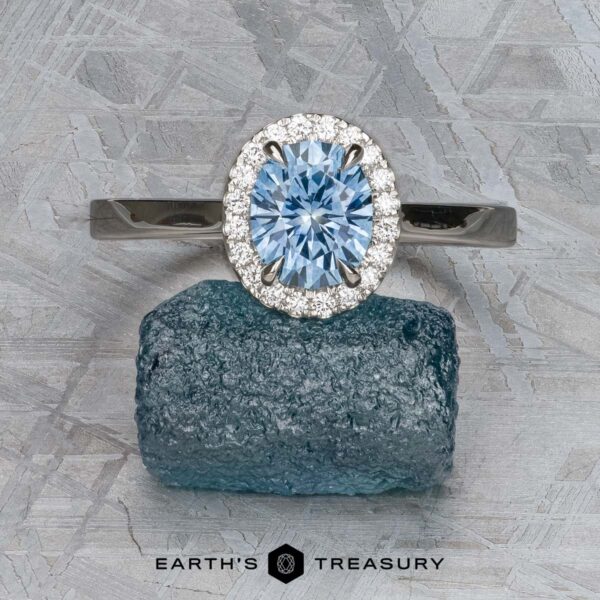 The "Alice" ring in platinum with 1.09-carat Montana sapphire The "Alice" ring in platinum, featuring a 1.09-carat Montana sapphire surrounded by diamonds, is displayed atop a rough blue crystal with "Earth's Treasury" text below.