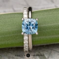 The "Cathedral" ring in platinum features a 1.63-carat Montana sapphire, paired with the classic pave straight band in platinum, both displayed on a green leafy stem.