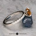 The Deluxe Pave "Claire" ring in platinum, featuring a 2.05-carat Montana sapphire, is showcased atop a rough blue stone.