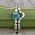 The "Clemencia" ring in platinum with a 1.07-carat Montana sapphire and the "Clemencia" band in platinum rest on a green leaf, with the Earth's Treasury logo below.