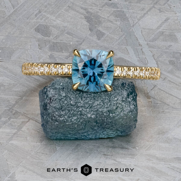 The Tapered Pave "Claire" ring in 18k yellow gold with 1.36-carat Montana sapphire The Tapered Pave "Claire" ring in 18k yellow gold, featuring a 1.36-carat Montana sapphire and accent diamonds, is shown on a rough blue stone.