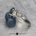 The "Juniper" ring in platinum with a 1.63-carat Montana sapphire rests on a rough blue mineral atop a textured gray surface, with the Earth’s Treasury logo at the bottom.