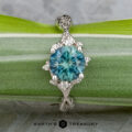 The "Juniper" ring in platinum features a 1.63-carat Montana sapphire in an ornate setting, displayed on a green leaf. The Earth's Treasury logo is shown at the bottom.