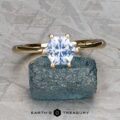 The “Vanessa” Ring in 14K yellow gold with a 1.08-carat Montana sapphire is displayed upright on a rough blue stone, against a textured gray background. The text "EARTH'S TREASURY" appears below.