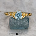 The “Siobhan” ring in 18K yellow gold, featuring a 1.02-carat oval Montana sapphire, is displayed on a rough blue stone with the "EARTH'S TREASURY" logo below.