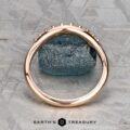 The "Hesperia" band in 20K pink gold stands upright, framing a rough blue gemstone on a textured gray surface, with the "Earth's Treasury" logo at the bottom.