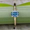 The "Clarice" ring in 14K yellow gold with a 0.97-carat Montana sapphire rests on a green leaf.