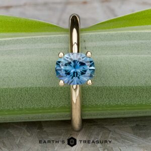 The "Clarice" ring in 14K yellow gold with a 0.97-carat Montana sapphire rests on a green leaf.