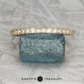 The Classic Pave Notched Band in 14K yellow gold is displayed on a rough blue gemstone against a textured gray background, with the logo "EARTH'S TREASURY" visible at the bottom.