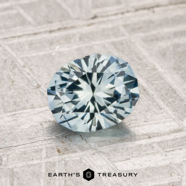 1.10-Carat Montana Sapphire (Heated) A 1.10-carat heated Montana sapphire, faceted in an oval cut, is shown on a textured light surface with the Earth's Treasury logo below.