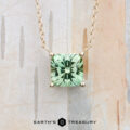 The "Glow" necklace in 14K yellow gold features a 1.59-carat square-cut Kornerupine pendant, shown on a light wood background with the Earth's Treasury logo at the bottom.