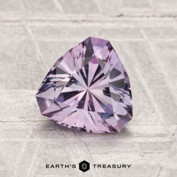 1.42-Carat Montana Sapphire A 1.42-carat trilliant-cut light purple Montana Sapphire displayed on a textured surface with the Earth's Treasury logo at the bottom.