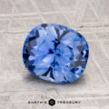 A 2.21-carat Ceylon sapphire with a cushion cut is displayed on a textured surface, with the text "EARTH'S TREASURY" shown below.