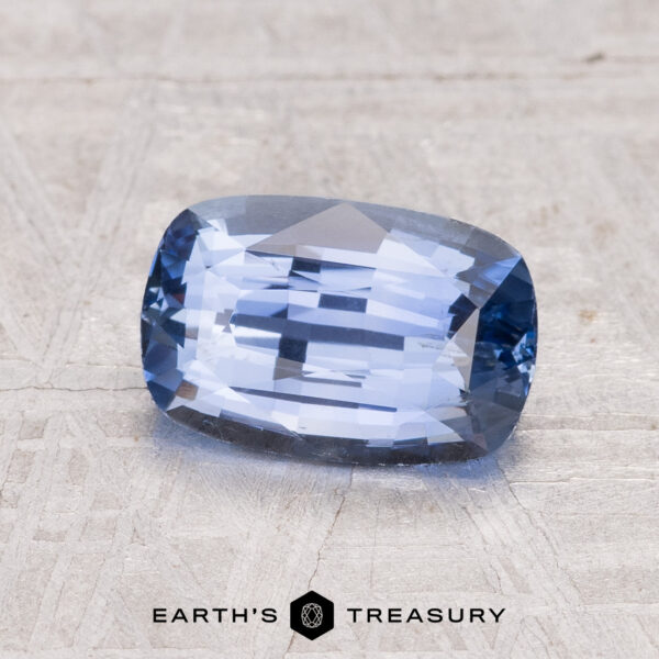 A 2.02-carat Ceylon sapphire in a rectangular cushion cut is shown on a textured gray surface with "EARTH'S TREASURY" displayed beneath.