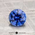 A 1.40-carat heated Ceylon sapphire is displayed on a textured, light gray surface with "Earth's Treasury" branding below.